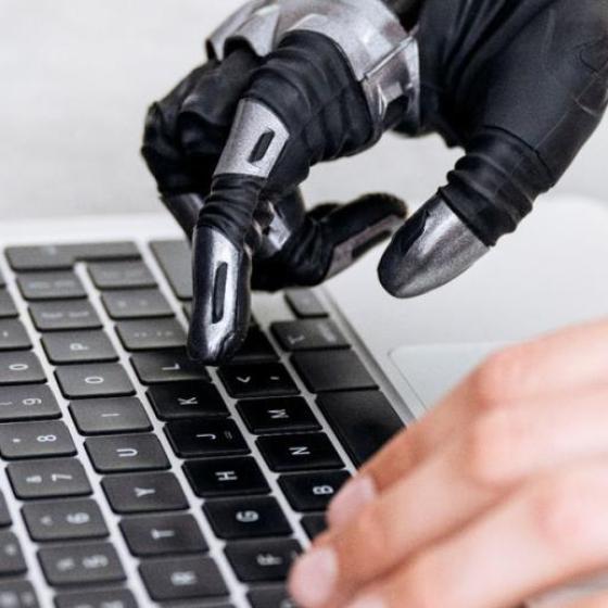 Imagen de unas manos (una de ellas es una prótesis) escribiendo en un ordenador.